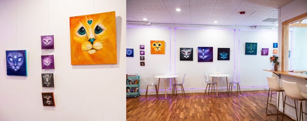 A wall of cat-themed local art displayed inside the cafe for monthly rotation.