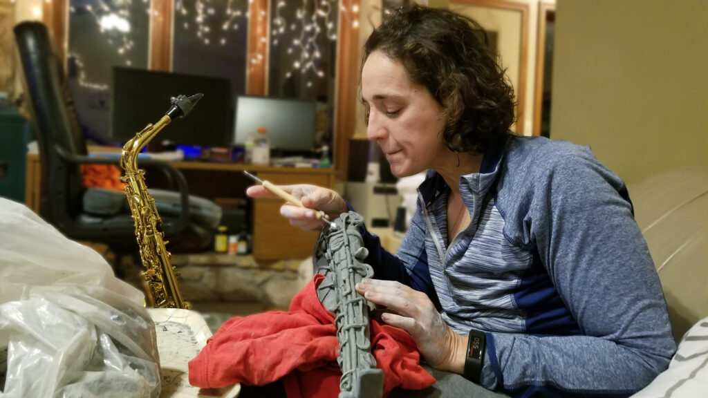 Tammy Karin carving details into clay saxophone