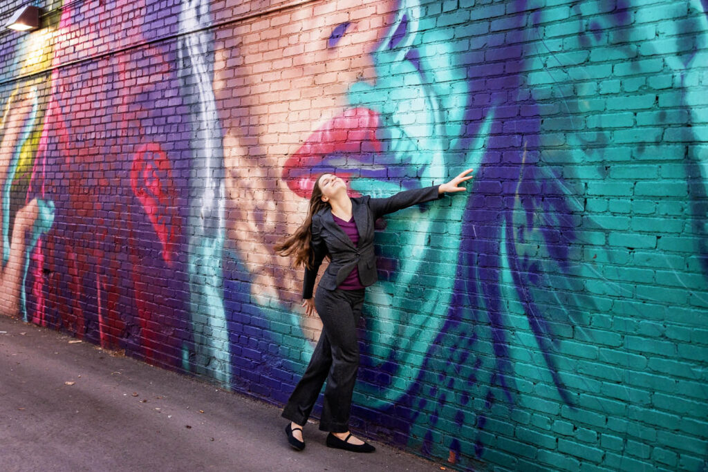 Young woman in front of a large scale mural in the Crossroads district.