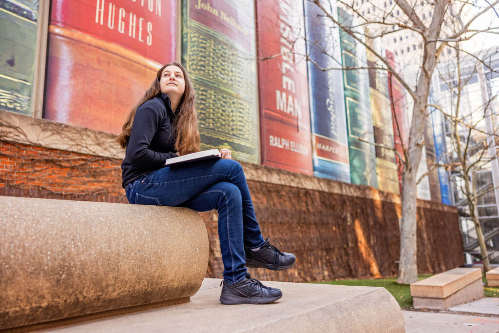 A bold portrait in front of the Community Bookshelf mural in Kansas City.