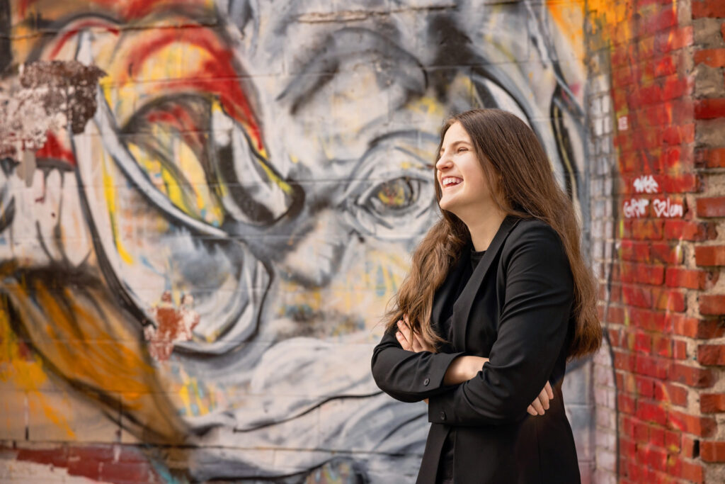 A high-contrast portrait in front of a colorful mural in East Lawrence.
